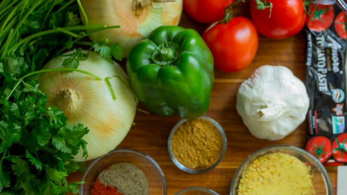 An assortment of fresh vegetables and spices on a wooden table for healthy cooking.