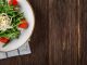 A delightful arugula salad with tomatoes and cheese, served on a rustic wooden table, perfect for healthy eating.