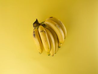 A vibrant bunch of ripe bananas on a matching yellow background, evoking freshness.