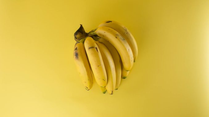 A vibrant bunch of ripe bananas on a matching yellow background, evoking freshness.