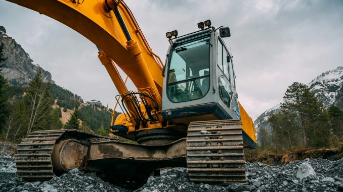 yellow and green excavator on rocky ground during daytime